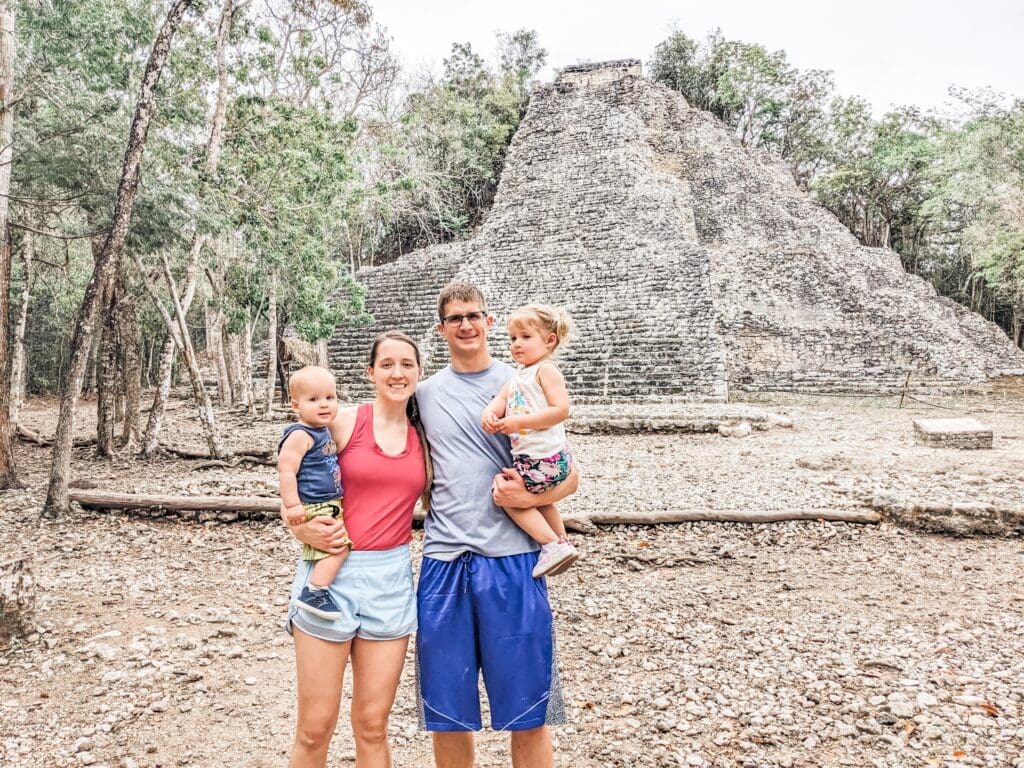 Family of four standing together in front of the Coba Mayan ruins, capturing a memorable moment during our family trip to Mexico.